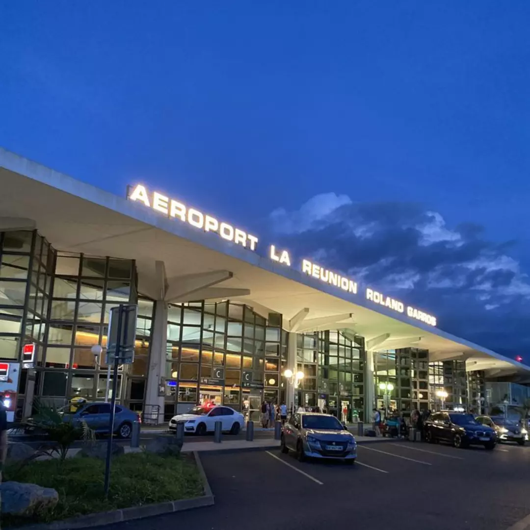 Voyageurs récupérant une voiture de location à l’aéroport de La Réunion pour commencer leur séjour et explorer l’île en toute liberté.